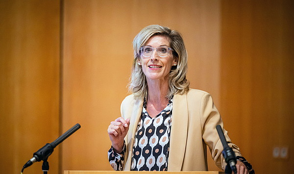 The picture shows a woman at the lectern in the Festsaal Fürstenhaus. Das Bild zeigt eine Frau am Rednerpult im Festsaal Fürstenhaus.