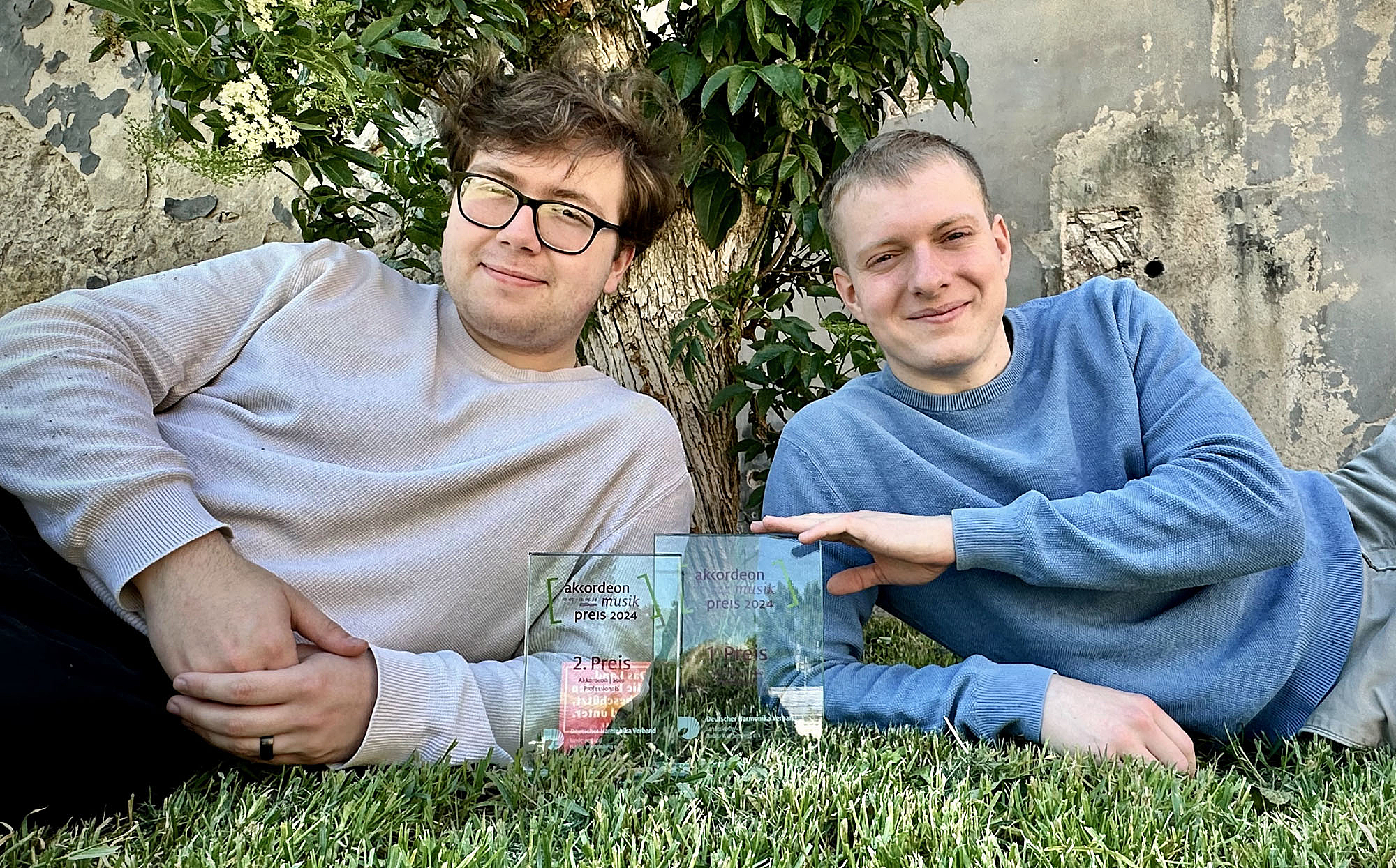 The picture shows two young men with glass trophies. Das Bild zeigt zwei junge Männer mit gläsernen Trophäen.