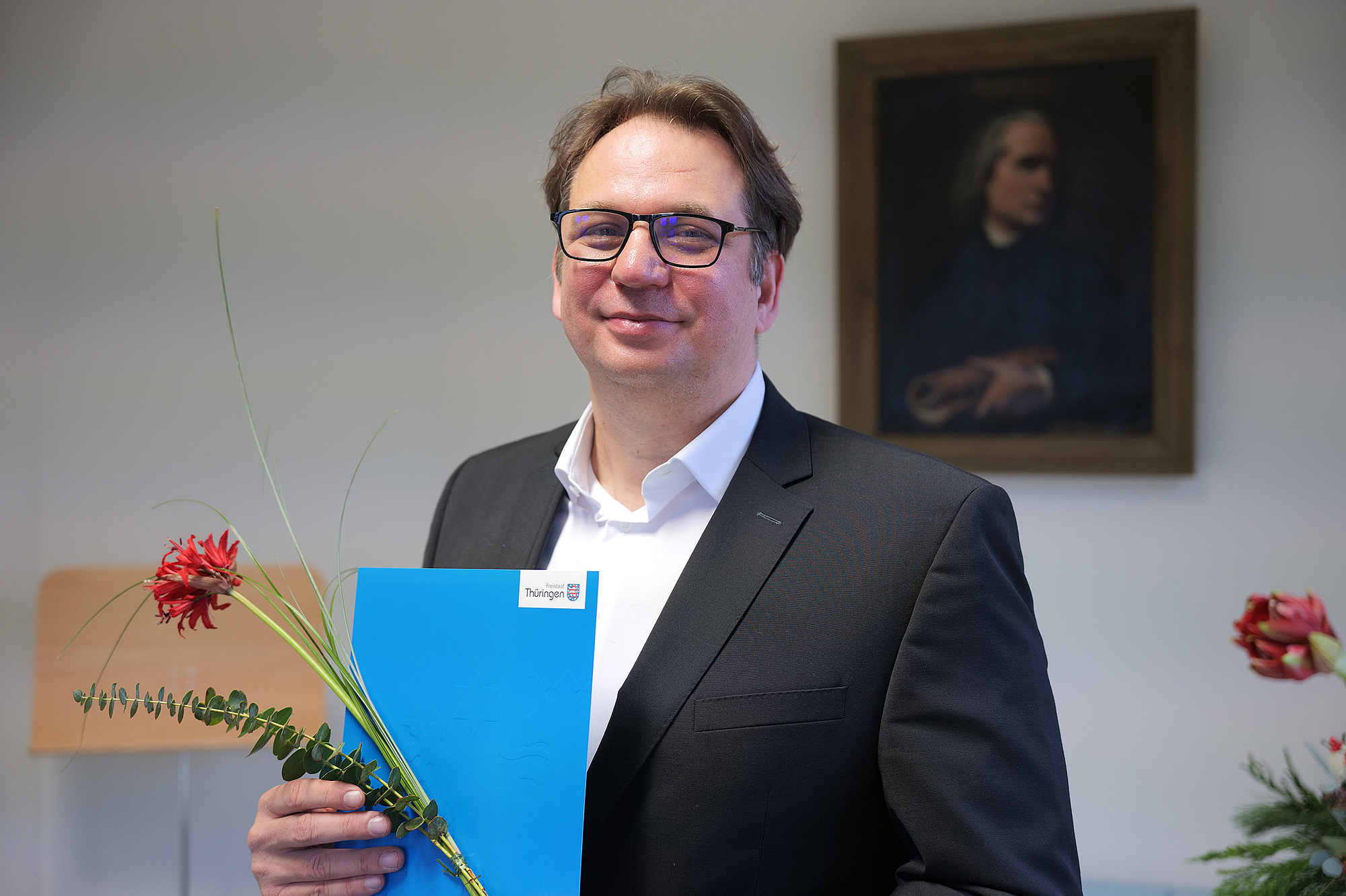 Das Bild zeigt eine Person mit einer Urkunde.