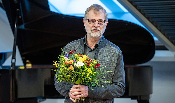 Das Bild zeigt einen Mann mit einem Blumenstrauß. 