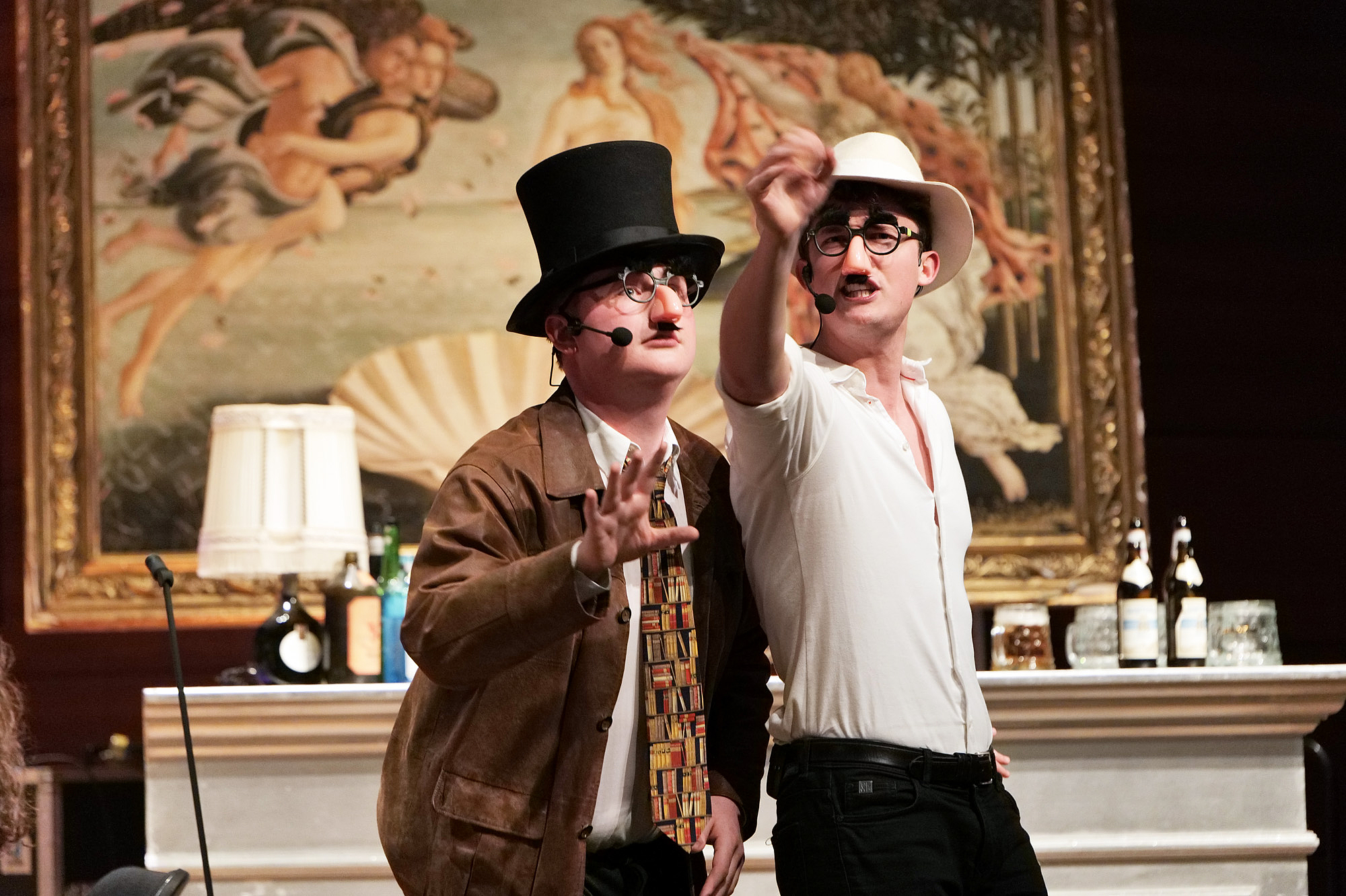 In the picture you can see two young men with hats and glued noses. Auf dem Bild sieht man zwei junge Männer mit Hüten und angeklebten Nasen.