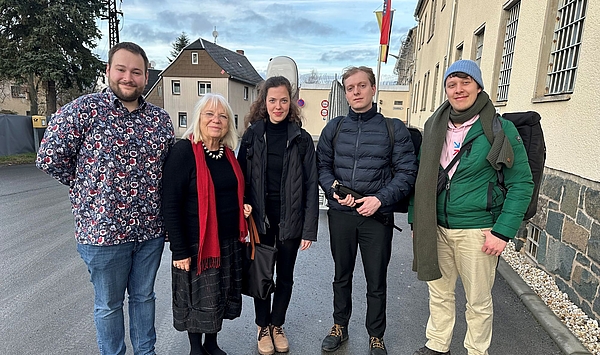 Auf dem Foto ist eine kleine Menschengruppe auf der Straße zu sehen.