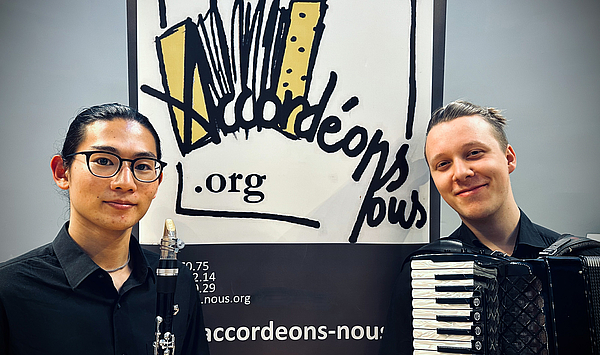 Das Bild zeigt zwei junge Männer mit Instrumenten. 