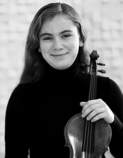 Young girl stands with her violin and looks into the photo. 