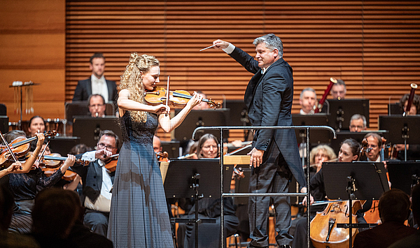 Das Bild zeigt eine Geigerin vor einem Orchester.