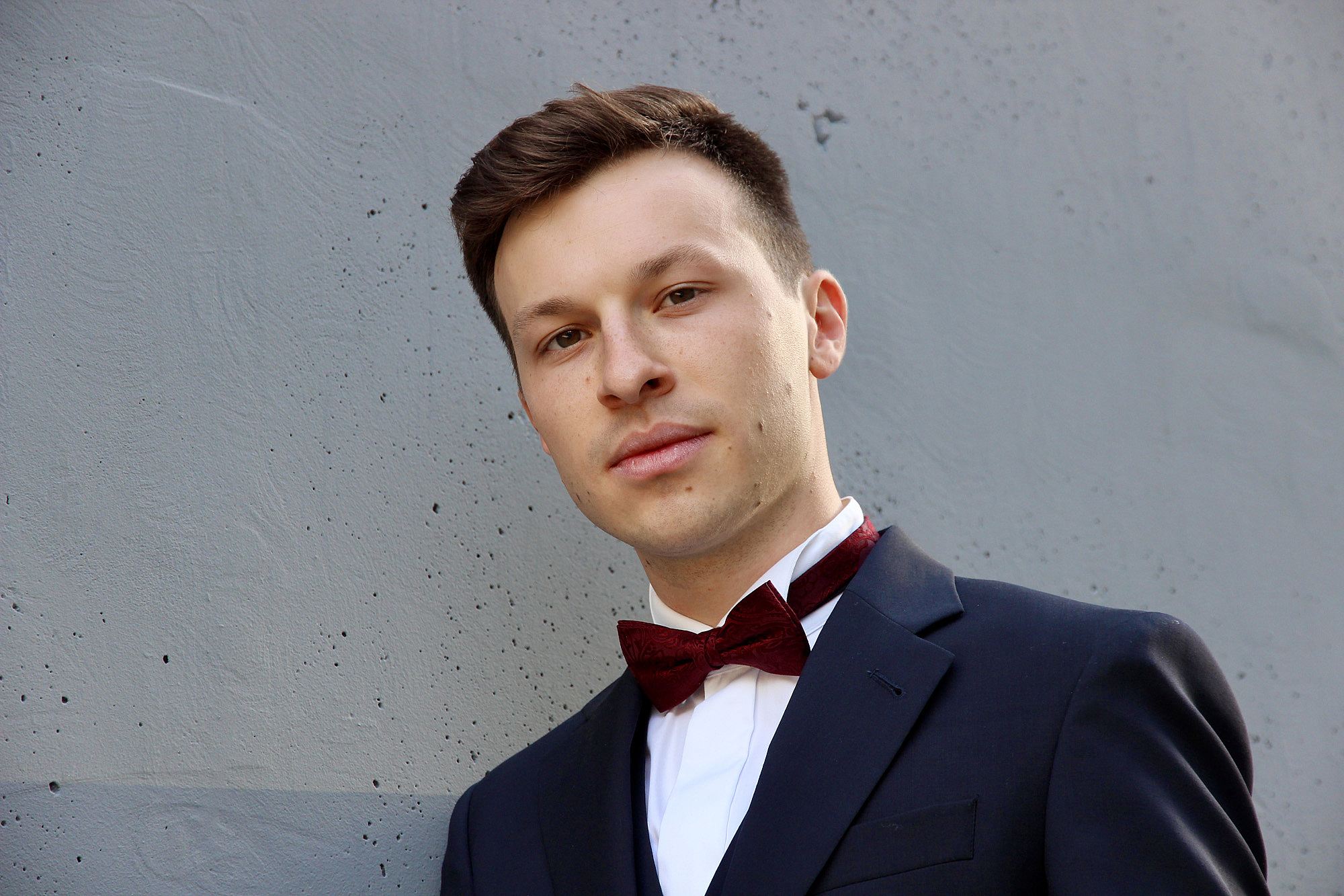 The picture shows a man in a suit with a bow tie. Das Bild zeigt einen Mann im Anzug mit Fliege.