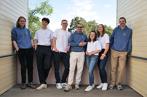 The picture shows a group of young people on a balcony. 