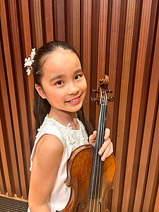The picture shows a child with a violin.