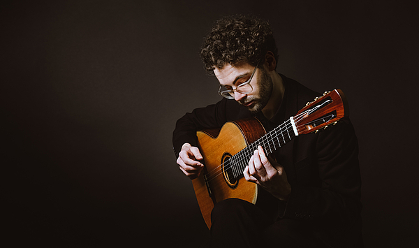 The picture shows a man with a guitar. Das Bild zeigt einen Mann mit einer Gitarre.