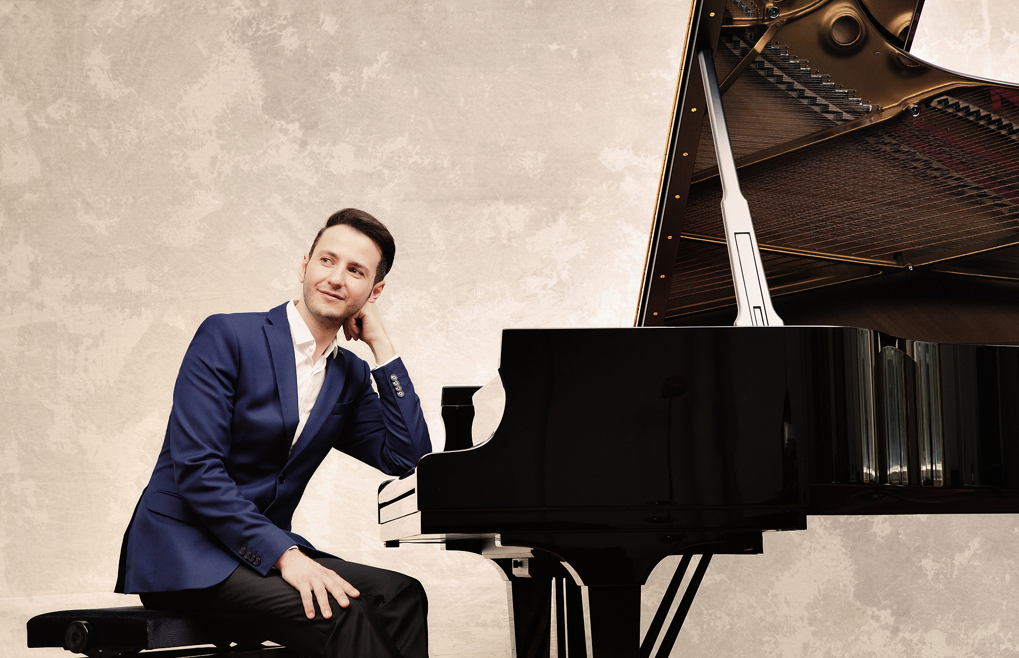 The picture shows a man in front of a grand piano. Das Bild zeigt einen Mann vor einem Konzertflügel.