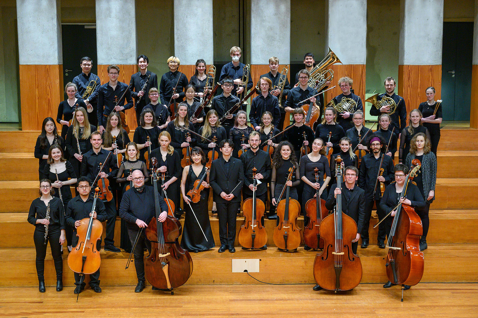 Das Bild zeigt ein Orchester auf Treppenstufen. 