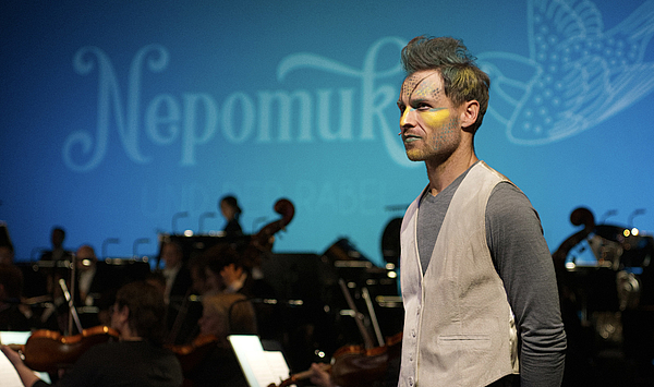 Das Bild zeigt eine Person vor einem Orchester.