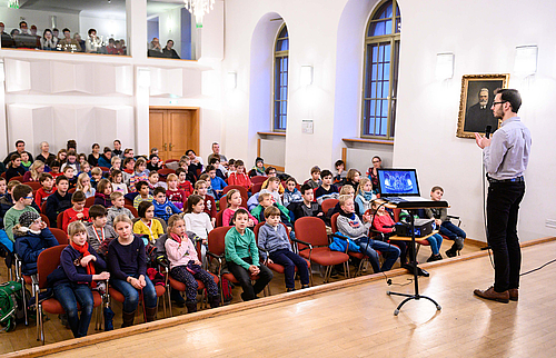 The picture shows a concert hall filled with young people.