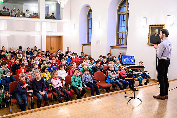 Das Bild zeigt einen Konzertsaal mit jungen Menschen.