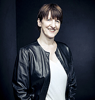 Woman in leather jacket against a dark background