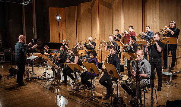 Das Bild zeigt junge Menschen, die auf einer Bühne in einem Orchester spielen.