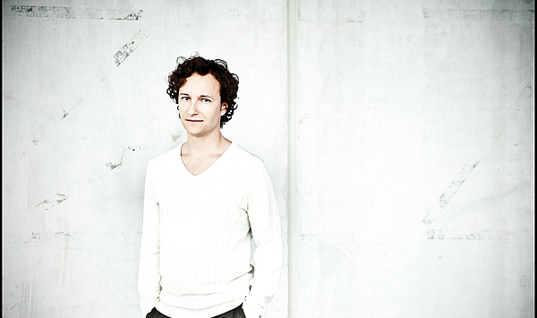 The picture shows a man in a white jumper. Das Bild zeigt einen Mann in weißem Pullover.