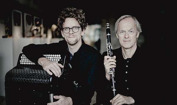 Das Bild zeigt zwei Personen mit Instrumenten.