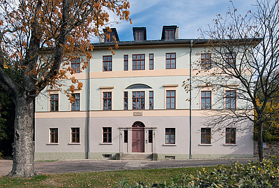 Das Bild zeigt ein hell gestrichenes historisches Gebäude. 