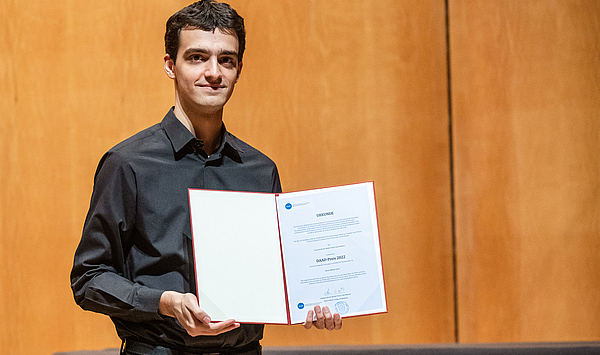 Der Geiger János Mátyás Stark hält seine DAAD-Preis-Urkunde hoch. 