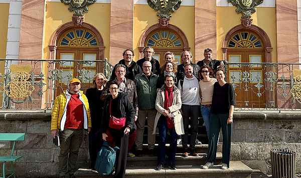 Das Bild zeigt eine Gruppe von Menschen vor einer historischen Fassade.