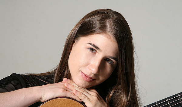 Das Bild zeigt eine Frau mit einer Gitarre.