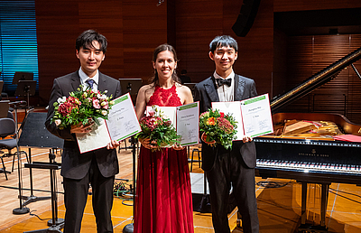 The picture shows three young people with flowers.