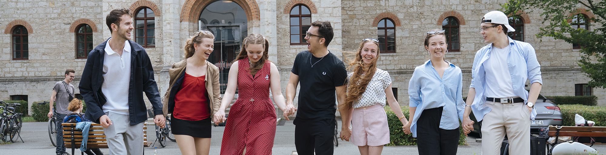 The picture shows seven young people in front of a building.