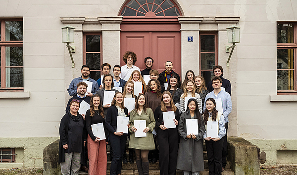 Das Bild zeigt eine Gruppe von Menschen vor einem historischen Gebäude.