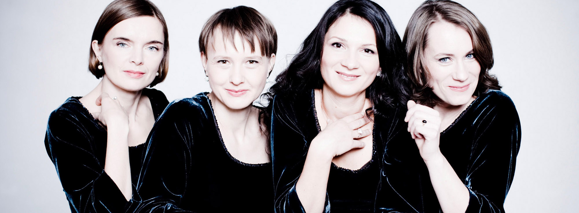 Vier Frauen blicken in die Kamera und stützen ihre Köpfe auf ihre Hände.