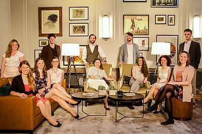 The picture shows young people in a parlour.