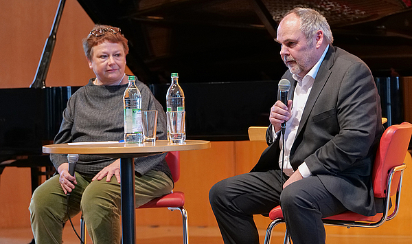 Das Bild zeigt einen Frau und einen Mann auf einer Bühne.