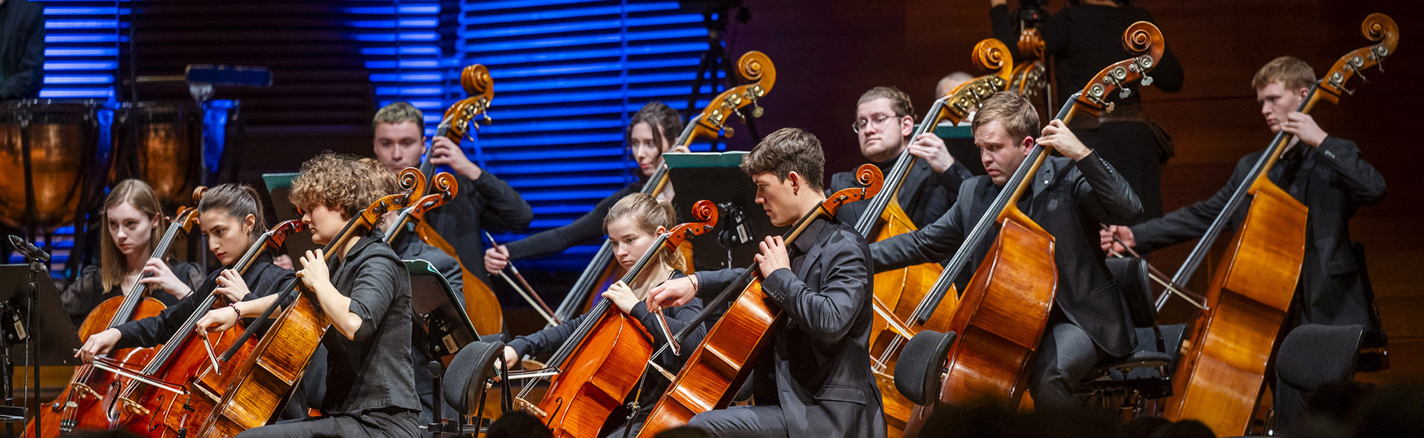 The image shows orchestra musicians on a stage.