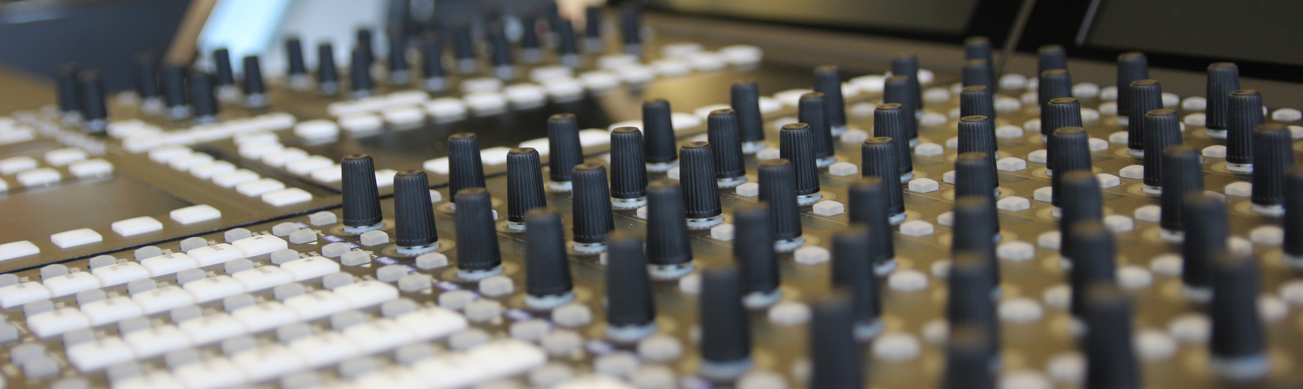 The picture shows a mixing desk in a recording studio.