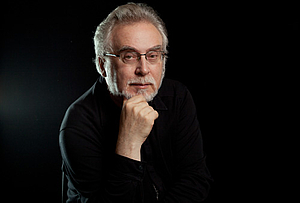 Portarit of a man dressed in black, black background