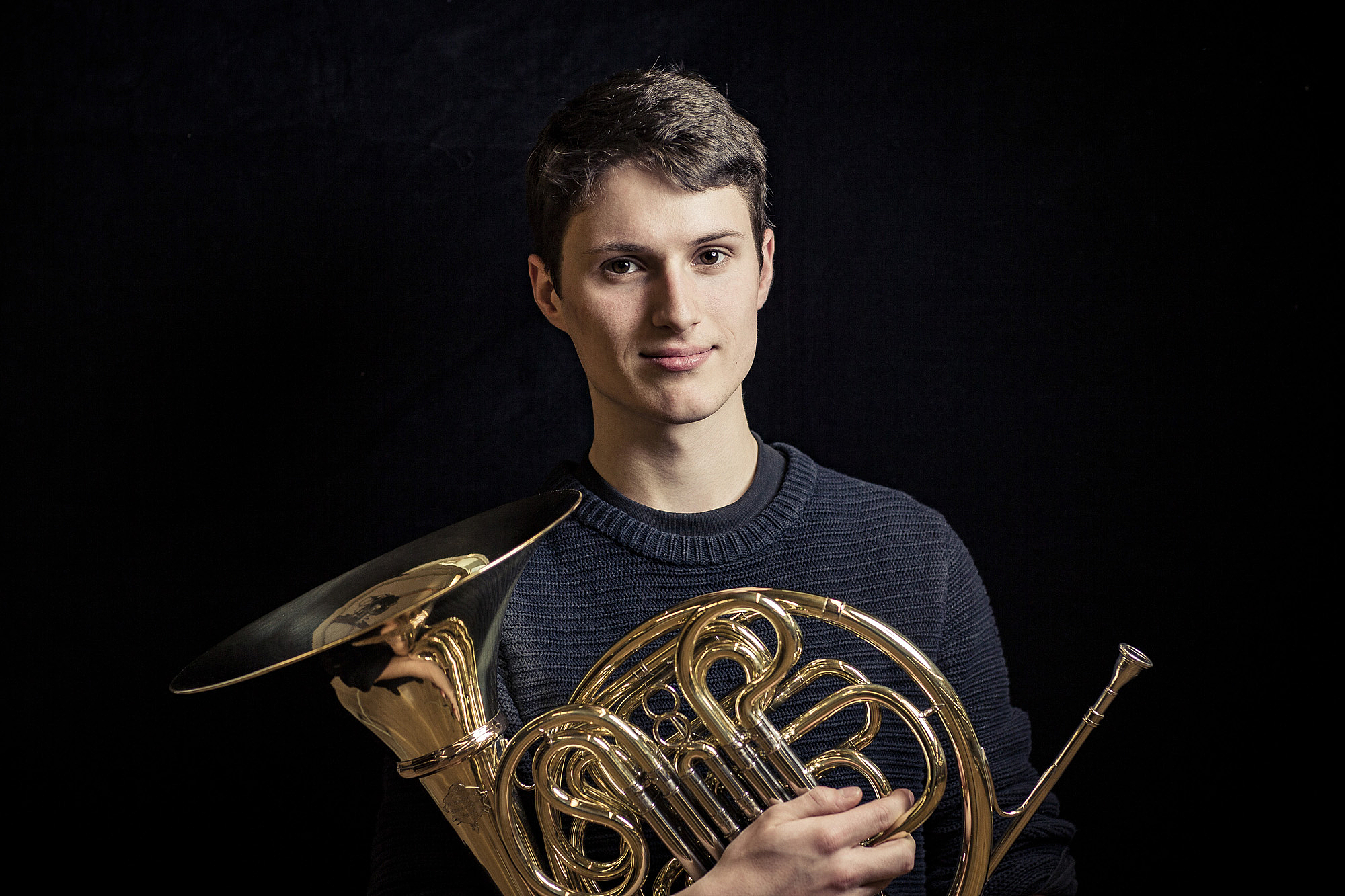 Das Bild zeigt einen jungen Mann mit einem Horn. 