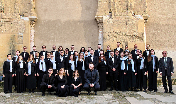 Das Bild zeigt eine Gruppe von Menschen vor einer Mauer.