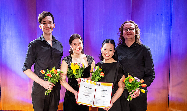 Das Bild zeigt vier junge Menschen mit Urkunden.
