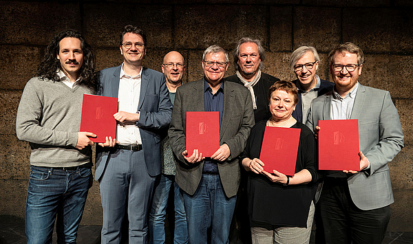 Das Bild zeigt acht Personen auf einer Bühne.