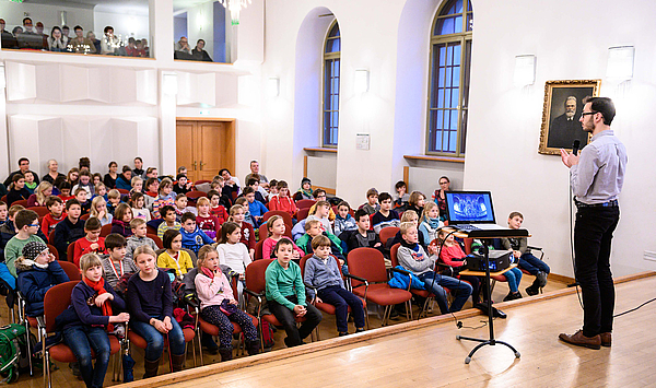 Das Bild zeigt einen Konzertsaal mit jungen Menschen.