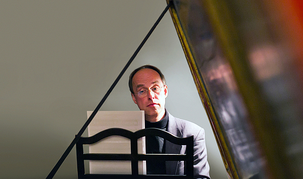 Das Bild zeigt einen Mann an einem Cembalo.