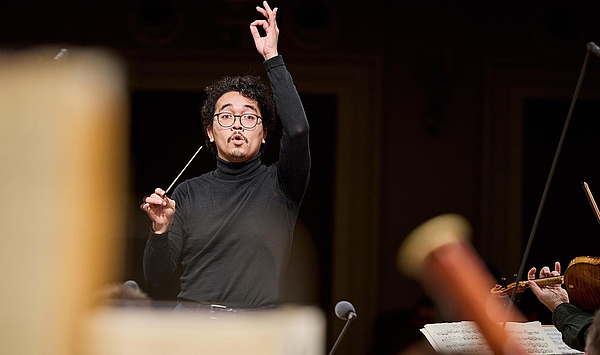 Das Bild zeigt einen Mann beim Dirigieren.