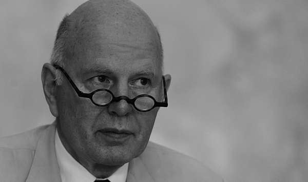 The picture shows a man looking over the rim of his glasses. Das Bild zeigt einen Mann, der über den Rand seiner Brille blickt.