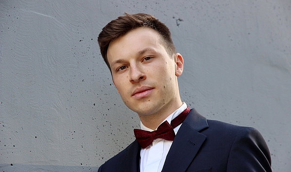 The picture shows a man in a suit with a bow tie. Das Bild zeigt einen Mann im Anzug mit Fliege.