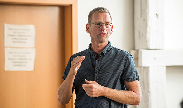 Das Bild zeigt einen Mann bei einem Vortrag.