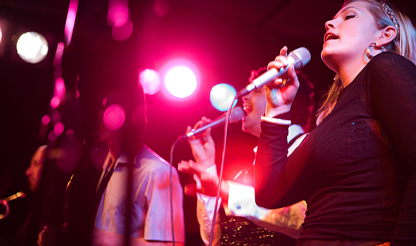 Das Bild zeigt eine singende Frau auf einer Bühne.