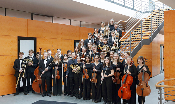 Das Bild zeigt junge Musiker*innen vor und auf einer Treppe.