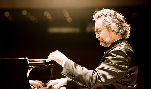 Das Bild zeigt einen Mann, der auf einem Klavier spielt. 