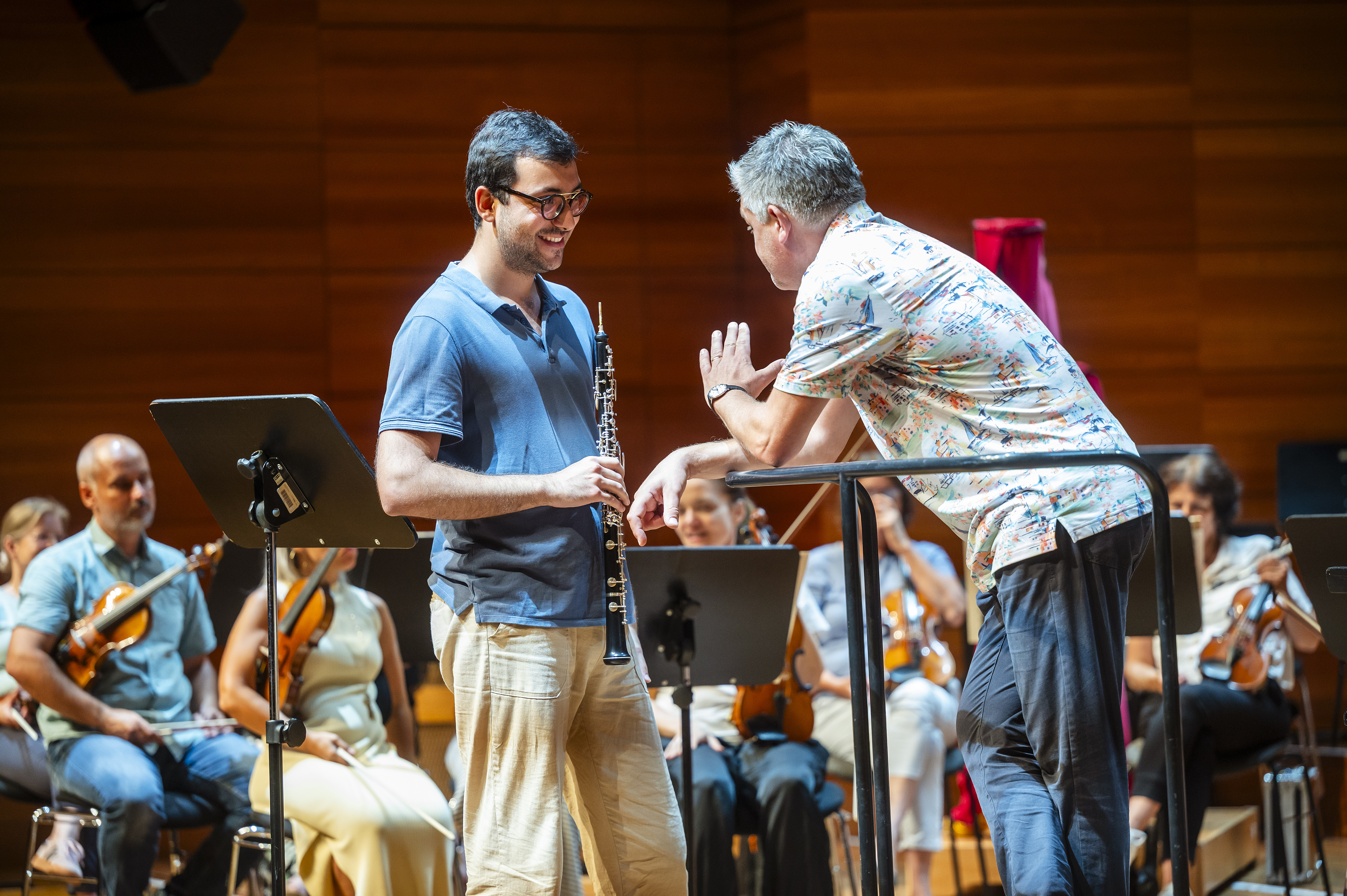 The picture shows a teacher and a student infront of a orchestra