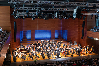 Das Bild zeigt ein Orchester auf einer Bühne.